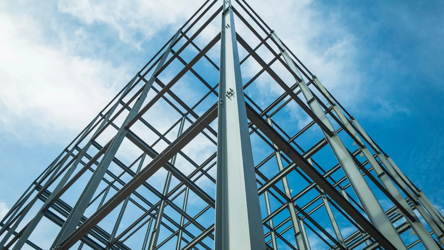 A structural grid made of high strength structural steel beams with clouds and blue skies in the background.