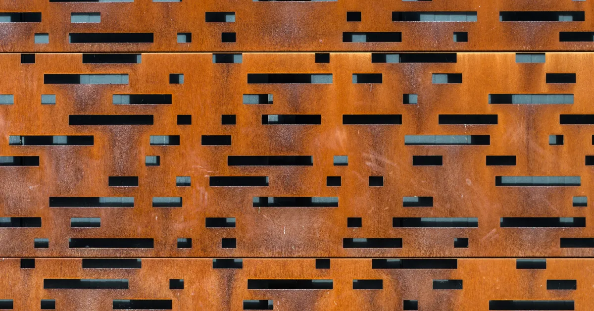 A textured rust-coloured perforated Corten steel sheet used for architectural design and cladding.